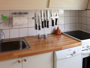 A kitchen with a wooden countertop, a sink, a stove, and a wall-mounted knife rack. - 5 Person Holiday Home in Mellbystrand (Mellbystrand)