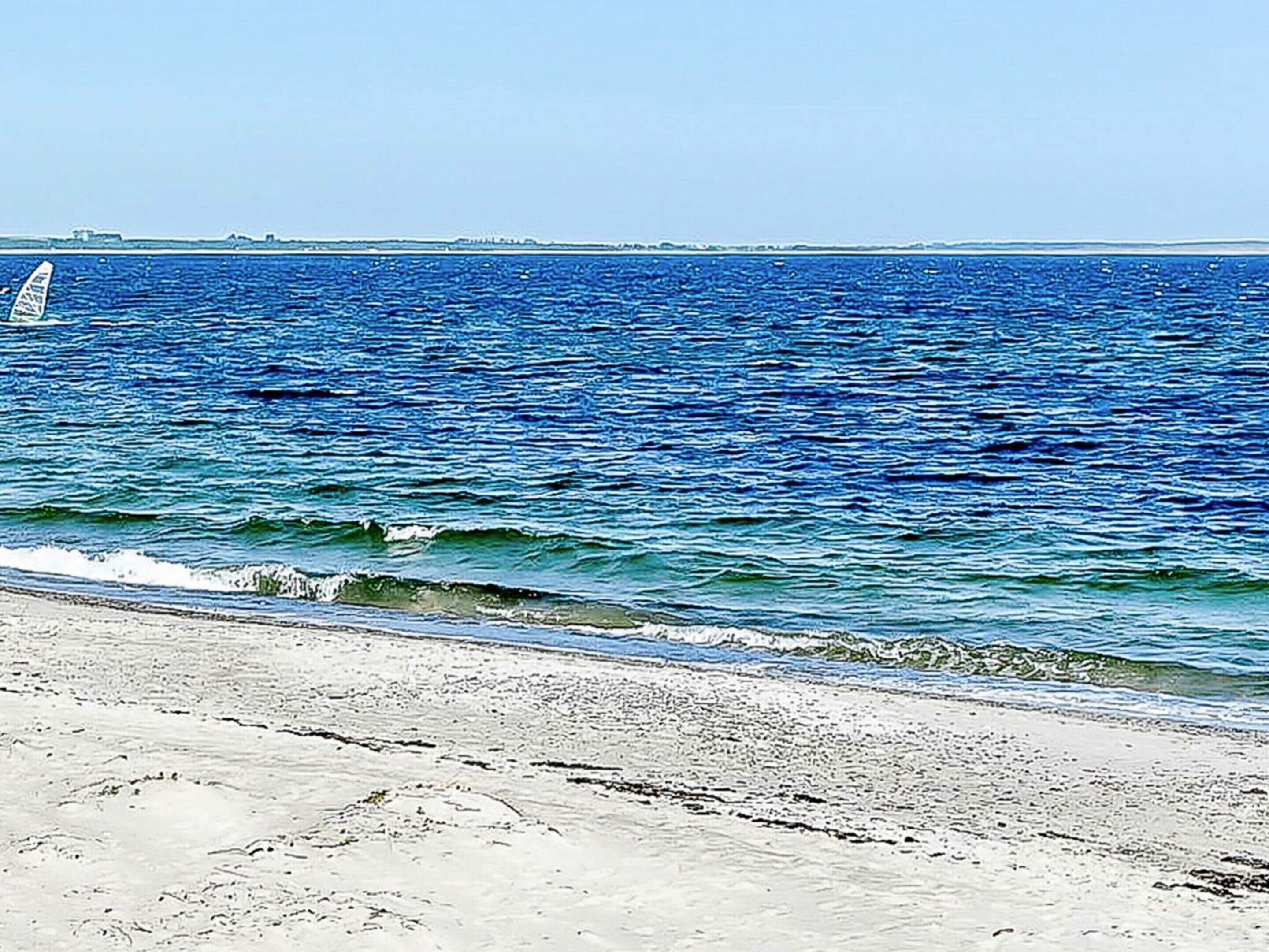 A beach with waves and a distant shoreline.