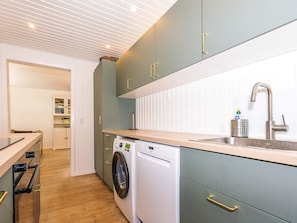 A modern kitchen with a built-in washing machine, a sink with a faucet, and wooden countertops.