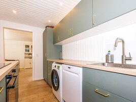 A modern kitchen with a built-in washing machine, a sink with a faucet, and wooden countertops.