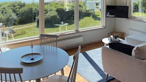 Een moderne woonkamer met een groot raam, met uitzicht op een meer en groen.