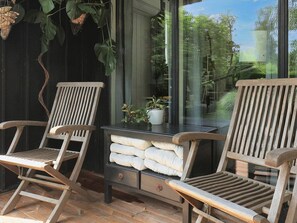 Una terraza de madera con dos mecedoras y una mesita con cojines.