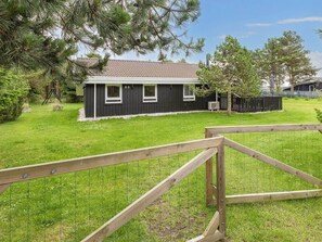 A residential property with a fenced yard, a house with a dark exterior, and a clear sky.