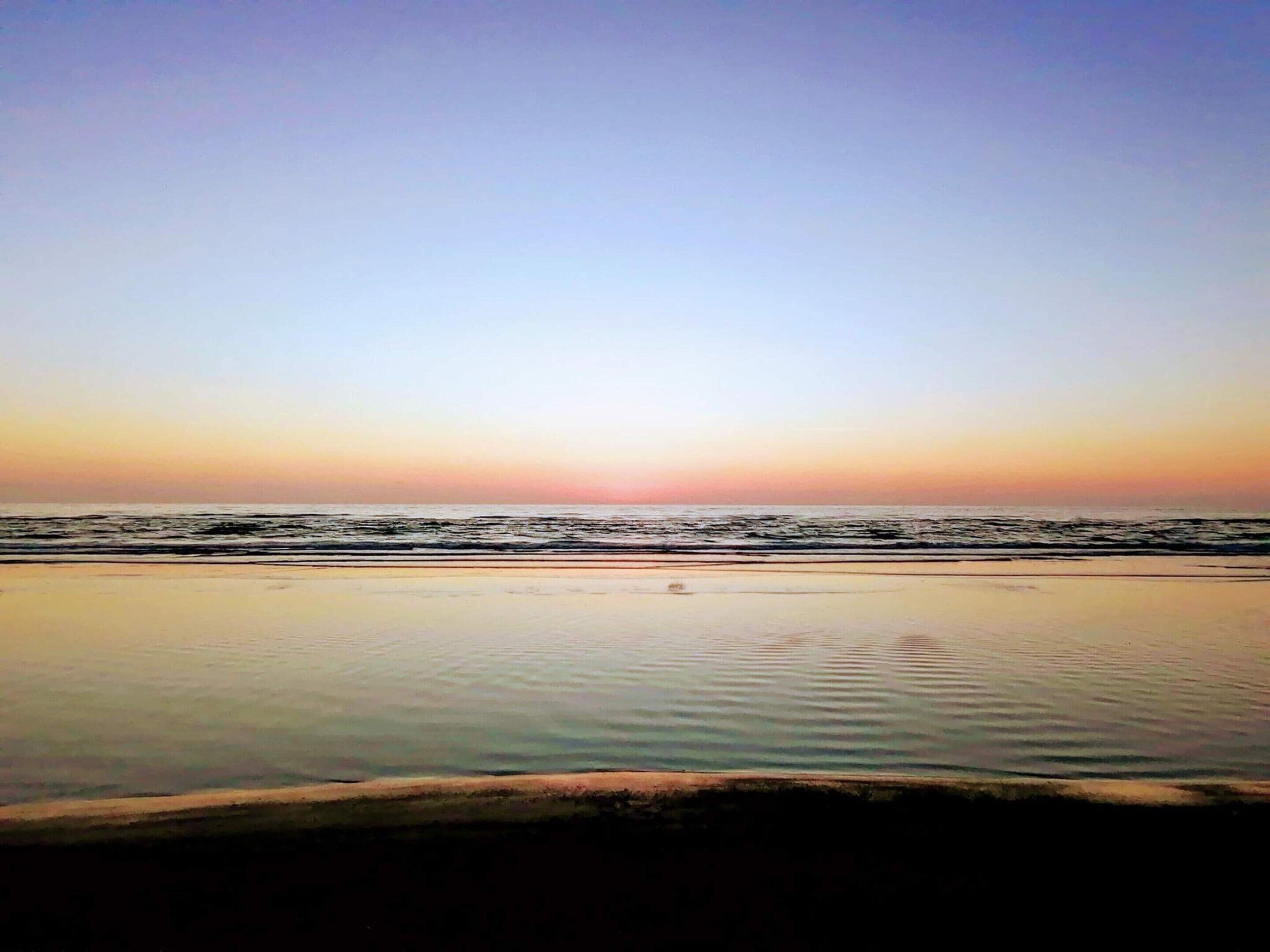 Une plage avec une mer calme et un ciel dégagé.