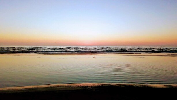 Une plage avec une mer calme et un ciel dégagé.