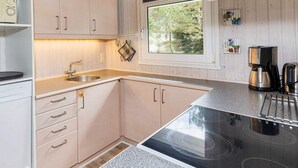 Une cuisine moderne avec des meubles de couleur bois clair, un évier en acier inoxydable et une cuisinière intégrée.