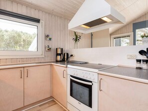 A modern kitchen with wooden cabinets, a Bosch oven, a coffee maker, and a window overlooking greenery.