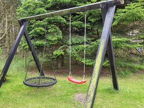 A swing set with a tire swing and a red seat, surrounded by greenery. - 4 Star Holiday Home in Lokken (Lokken)