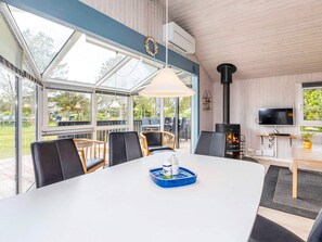 A modern dining area with a large table, chairs, and a television. - 4 Star Holiday Home in Lokken (Lokken)
