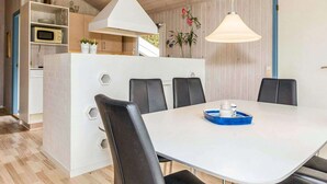 Un espace repas moderne avec une table blanche, des chaises noires et un plateau bleu.