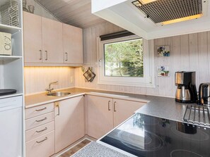 A modern kitchen with a built-in stove, stainless steel appliances, and a window with a view of greenery.