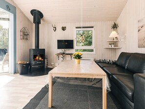 A modern living room with a fireplace, a sofa, a TV, and a dining area.