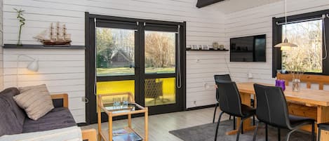 A modern interior with a dining area, a sofa, and a bookshelf.