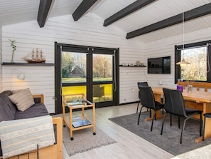A modern interior with a dining area, a sofa, and a bookshelf.