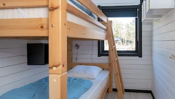 Habitación con literas, una escalera, una ventana y una lámpara en la pared.