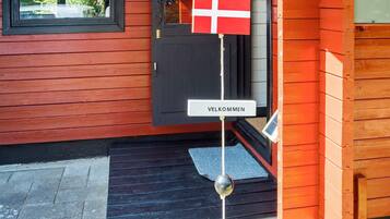 Una casa de madera con una puerta negra y una bandera roja.