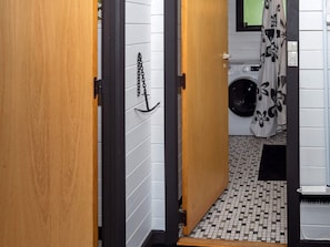 A bathroom with a tiled floor, a washing machine, and a shower curtain with a floral pattern. - 4 Person Holiday Home in Nibe (Nibe)