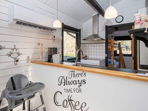 A kitchen with a wooden countertop, a coffee station sign, a sink, and a window with a view of greenery. - 4 Person Holiday Home in Nibe (Nibe)