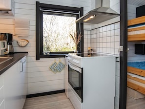 A compact kitchen with a window, a stove, and a sink. - 4 Person Holiday Home in Nibe (Nibe)