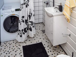A compact bathroom with a washing machine, a sink with a soap dispenser, and a toilet.