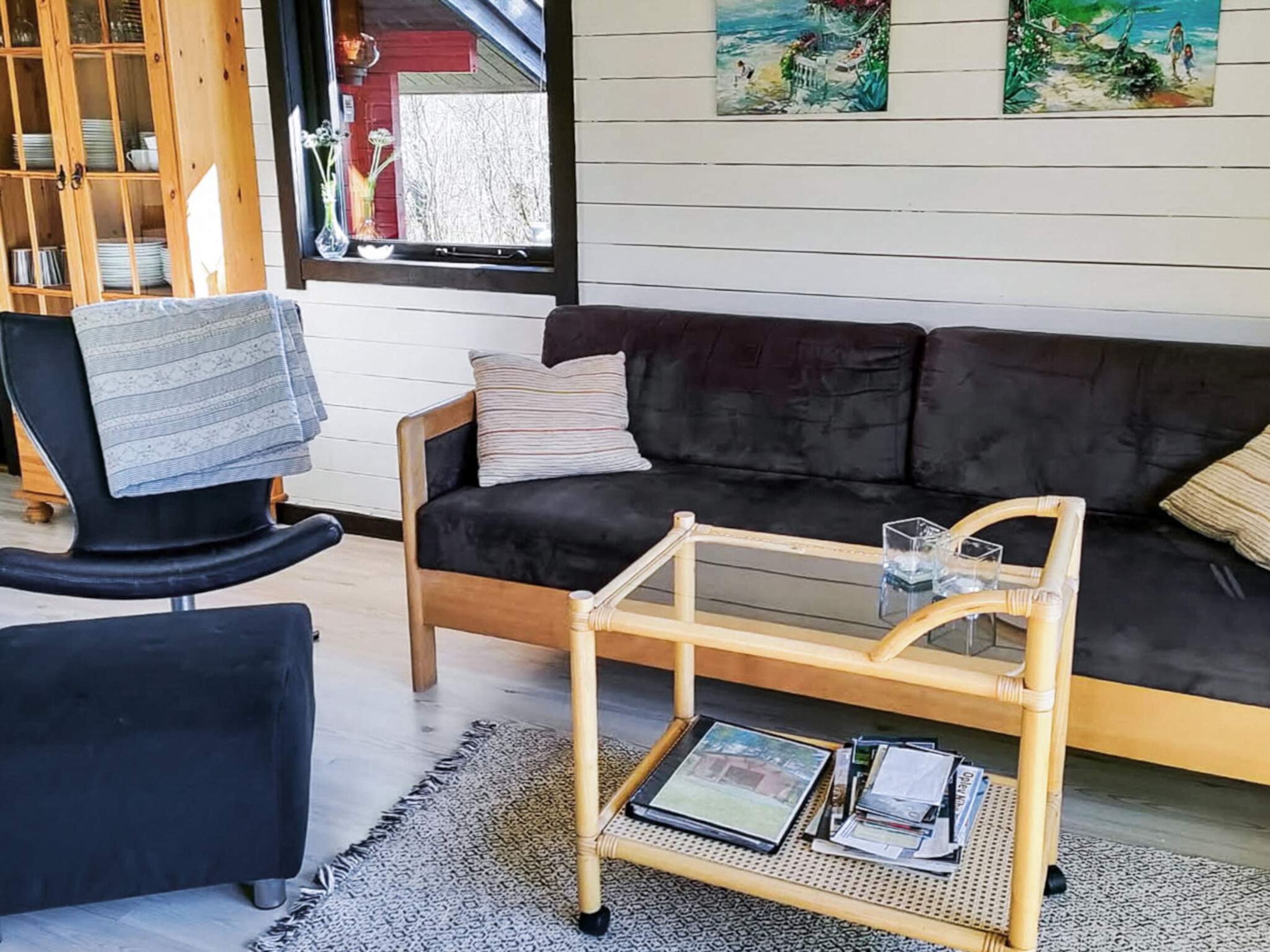 A living room with a black sofa, a wooden coffee table, and a black armchair.