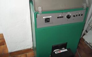 A green utility room with a control panel, a white wall, and a tiled floor.