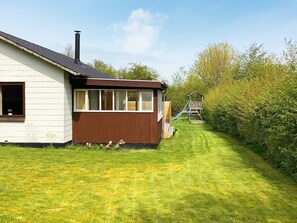 Una casa con un piccolo patio e uno scivolo nel giardino.