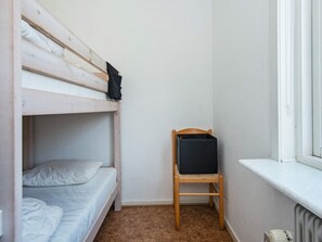 A small, compact room with a bunk bed, a single bed, a wooden chair, and a window. - 6 Person Holiday Home in Norre Nebel (Norre Nebel)