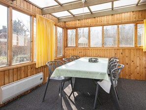 Una habitación con una mesa y sillas, ventanas amplias y un ventilador de techo.