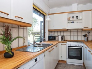 Una cocina compacta con armarios blancos, un horno Bosch, un microondas y un lavamanos.