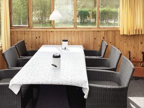 A dining area with a table and chairs, a window with curtains, and a hanging light fixture.