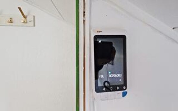 A room with a small window, a door, and a wall-mounted device.