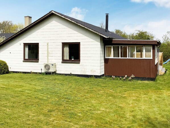 A single-story house with a white exterior and brown trim, a chimney, and a small porch area.