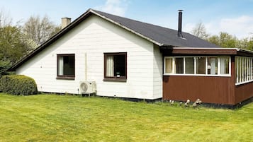 A single-story house with a white exterior and brown trim, featuring two windows and a chimney.