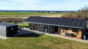 Una casa moderna con un amplio ventanal de vidrio, un patio espacioso y vistas al mar.