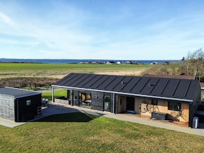 A modern house with a large glass facade, a spacious patio, and a view of the sea. - 10 Person Holiday Home in Vinderup-by Traum (Vinderup)