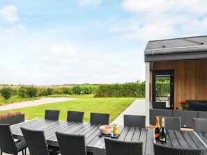 An outdoor dining area with a table and chairs, a view of the countryside, and a building with a wooden exterior. - 5 Star Holiday Home in Vinderup (Vinderup)