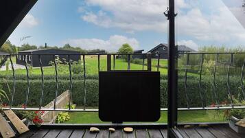A balcony with a view of a well-maintained lawn and houses in the distance.