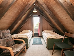 A small, cozy attic bedroom with two single beds, a wooden ceiling, and a view through a window. - 6 Person Holiday Home in Thyholm (Thyholm)
