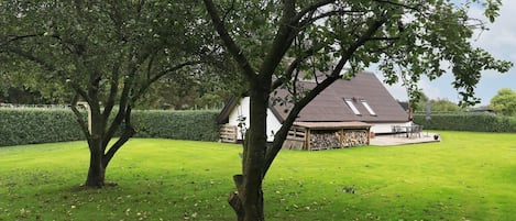 Ett hus med ett sluttande tak, en inglasad veranda och en välskött gräsmatta.