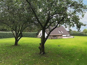 Uma casa com telhado inclinado, varanda coberta e gramado bem cuidado.