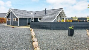 A modern house with a sloped roof, a covered patio, and a gravel driveway. - 5 Star Holiday Home in Ansager (Ansager)