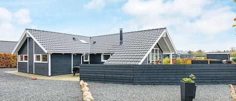 A modern house with a sloped roof, a covered patio, and a gravel driveway.