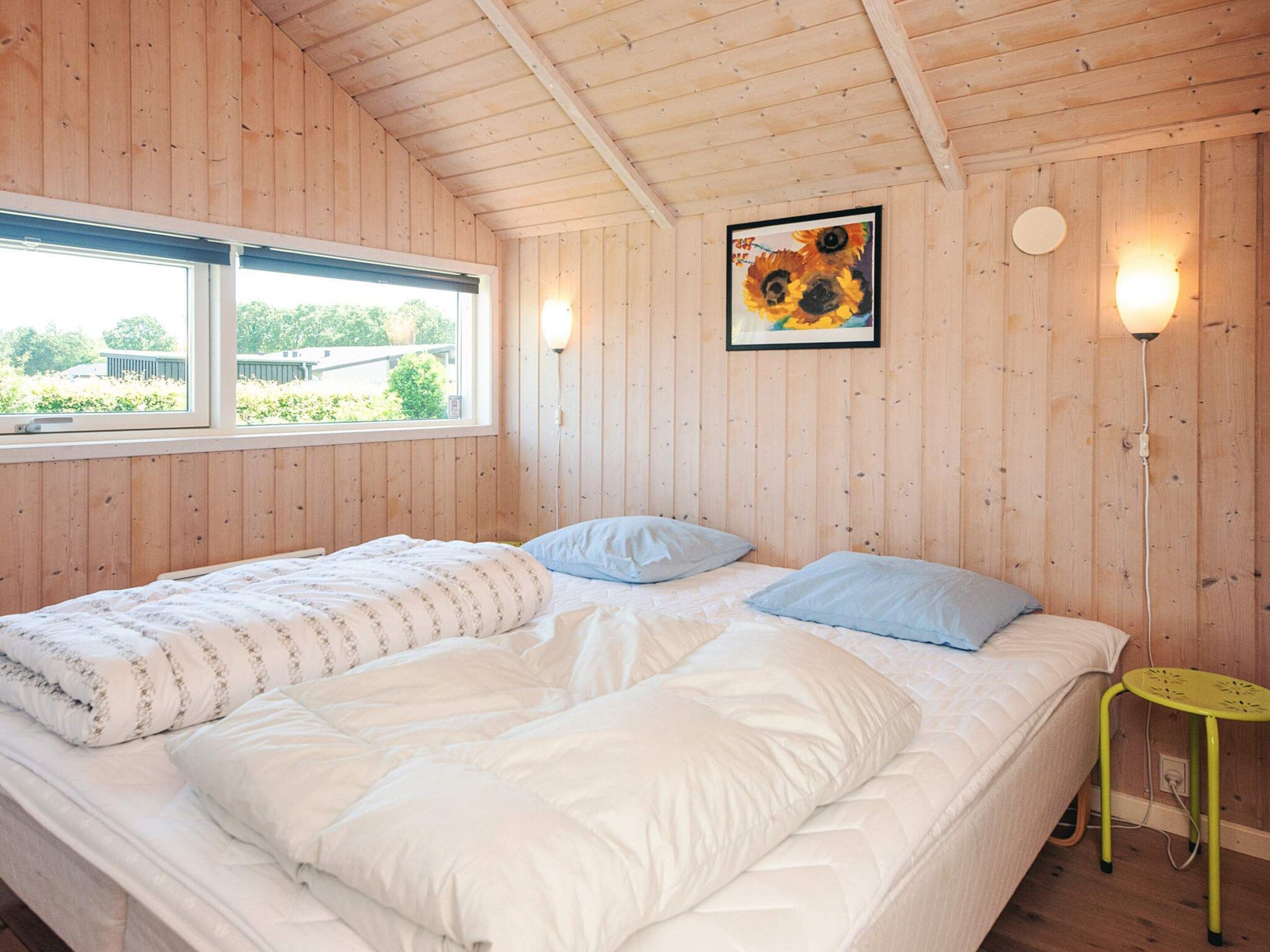 Een slaapkamer met een groot bed, een raam en een wandlamp.