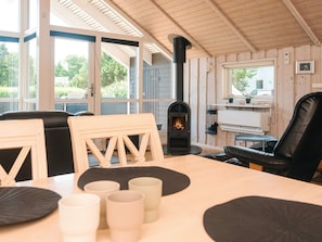 A cozy room with a fireplace, wooden walls, and a table with chairs.
