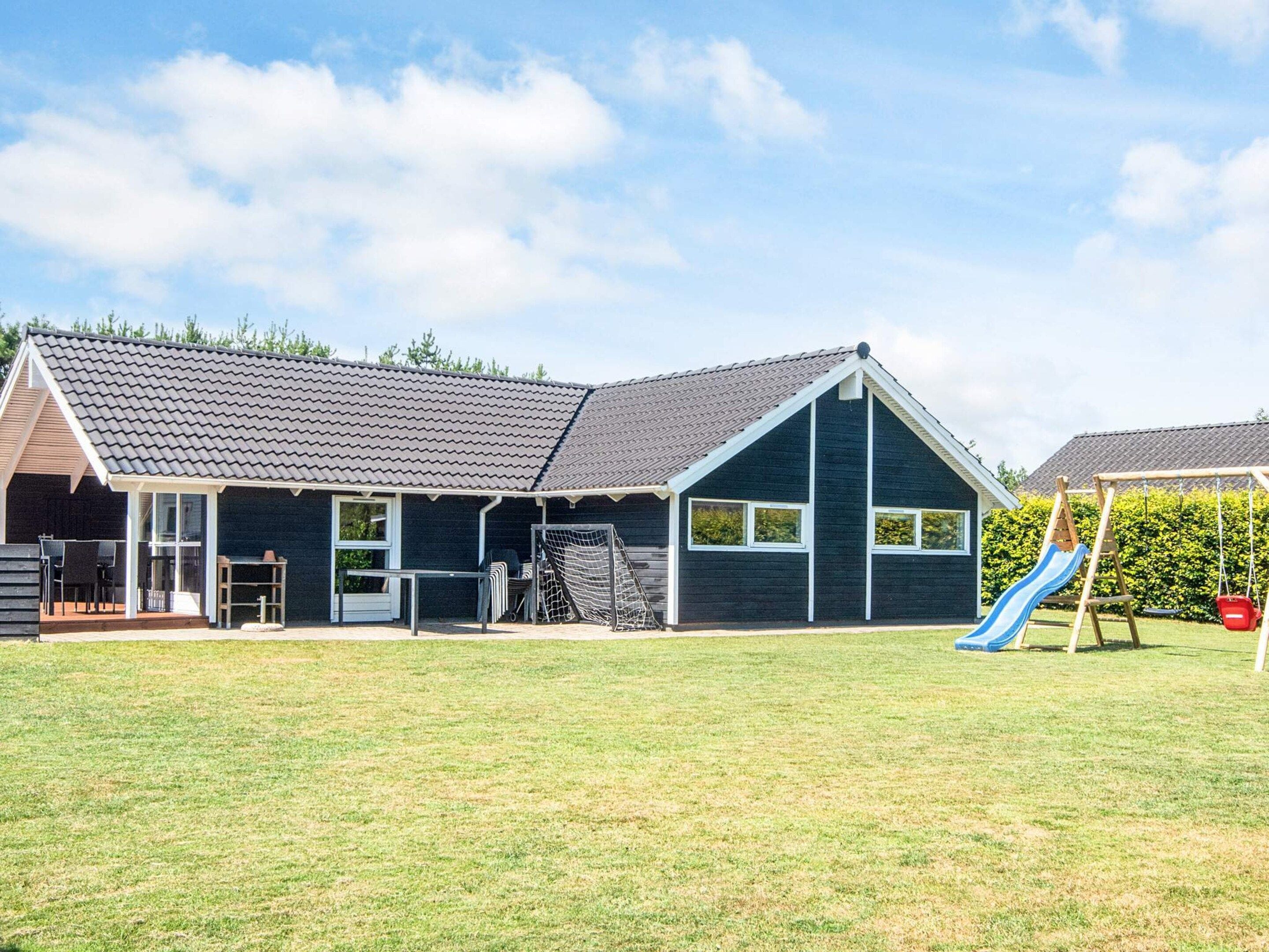 A house with a covered patio, a play area with a slide, and a tennis court.