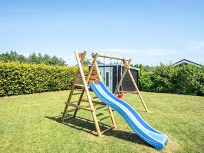 A wooden playset with a slide in a grassy yard.