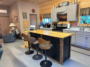 A kitchen with a bar area, wooden cabinets, a stove, and a water dispenser.