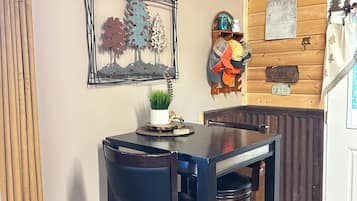 A wooden interior with a table and chairs, a sign indicating 'Trail 161 25 Frenchman CR', and various wall decorations including a notice board and a helmet.