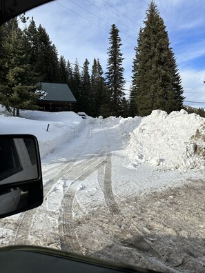 A snowy road with tire tracks, surrounded by snowbanks and tall evergreen trees. - The Shabin at Cardiff Spur (Pierce)